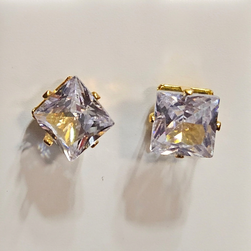 Close-up of square clear-stone stud earrings with gold-tone bar prongs