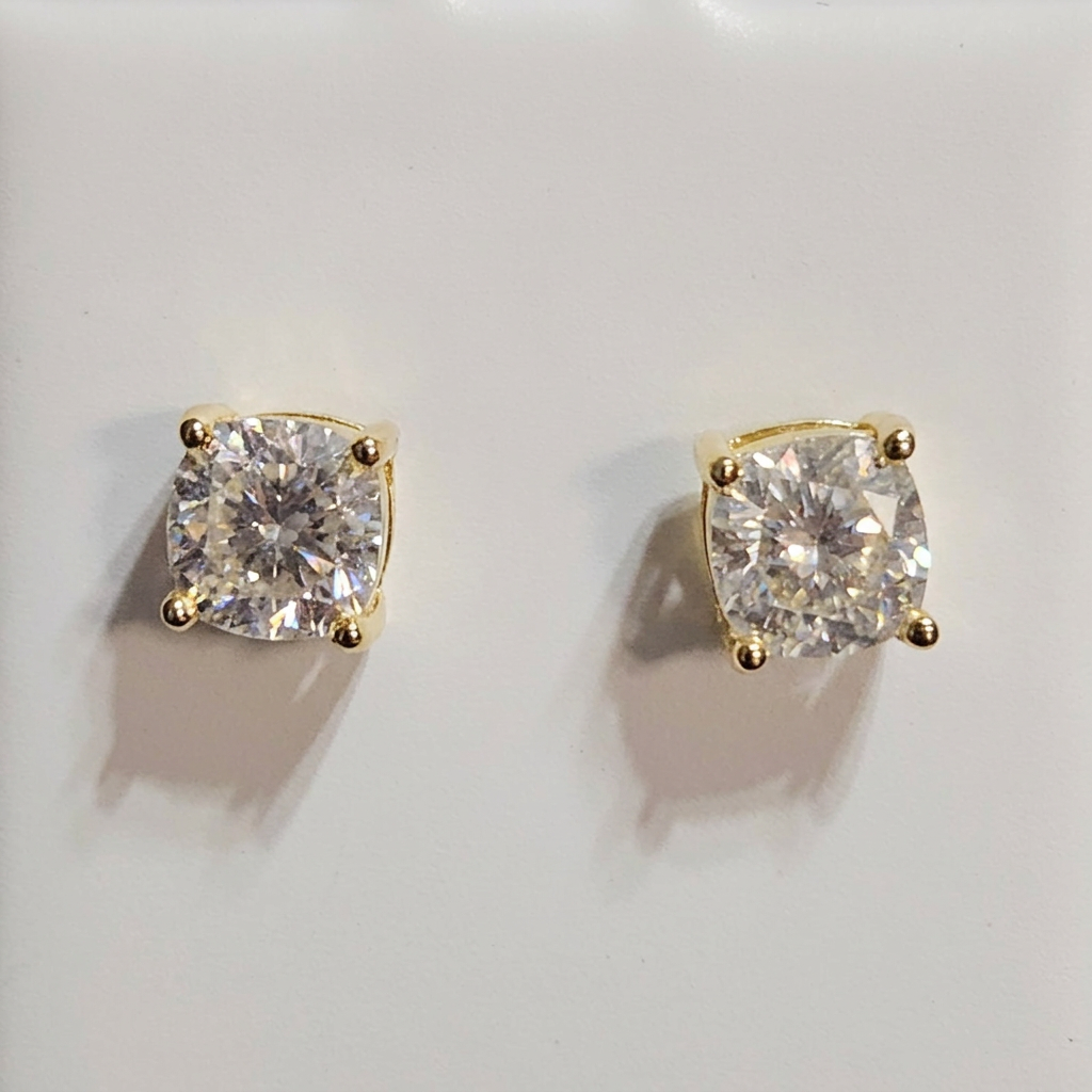 Close-up of clear-stone square stud earrings with gold-tone corner prongs