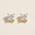 Close-up of square clear-stone stud earrings with gold-tone corner prongs