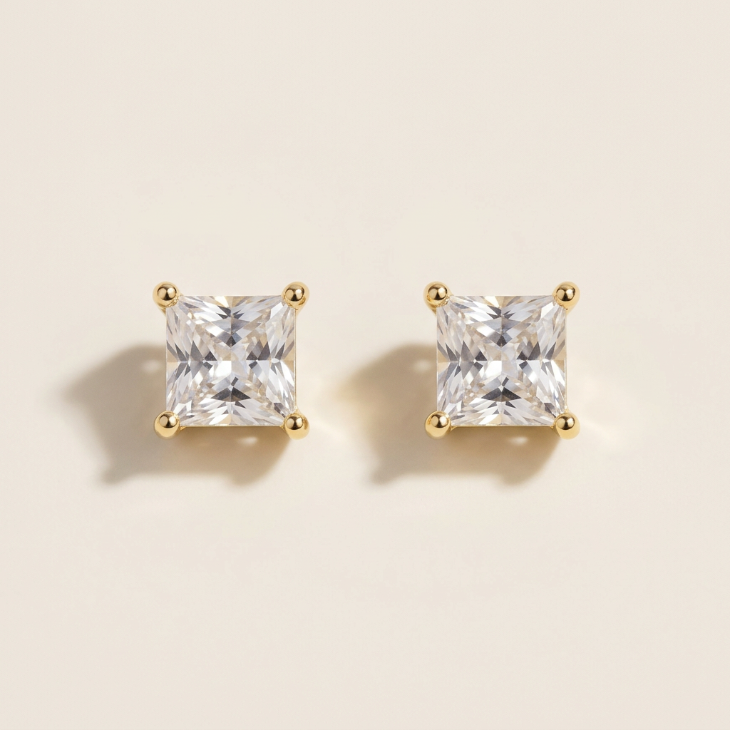 Close-up of square clear-stone stud earrings with gold-tone corner prongs