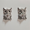 Close-up of silver-tone sparkling owl earrings