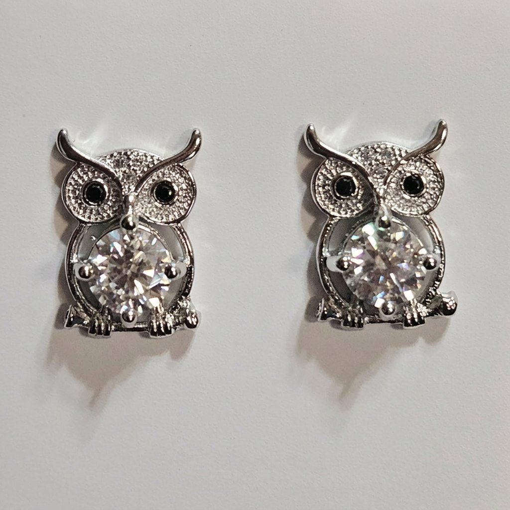 Close-up of silver-tone sparkling owl earrings